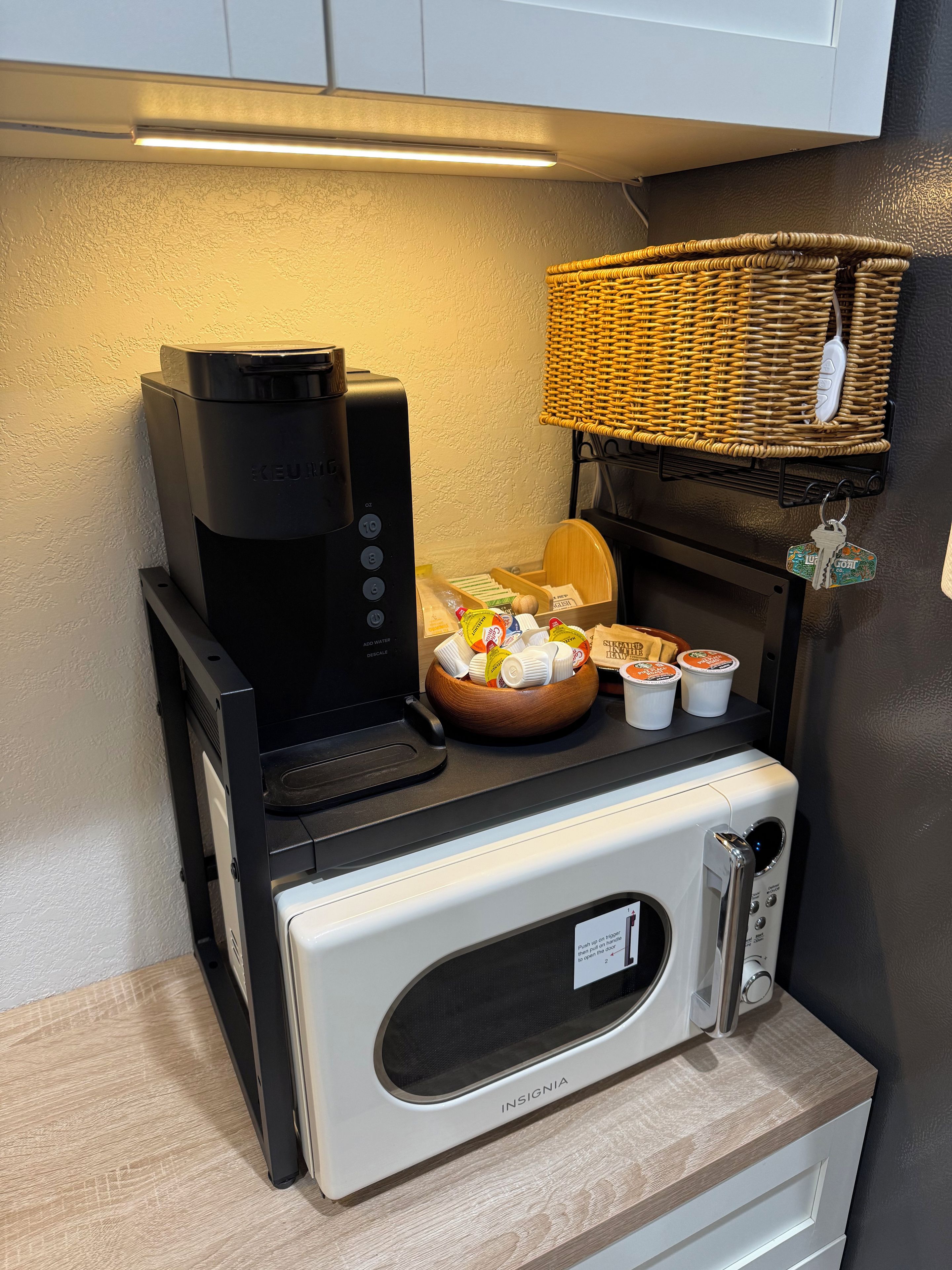 Une petite cuisine équipée d’une machine à café, d’un four à micro-ondes et d’un panier de pain.