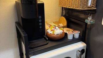 A kitchenette with a coffee maker, microwave, and a basket of bread.