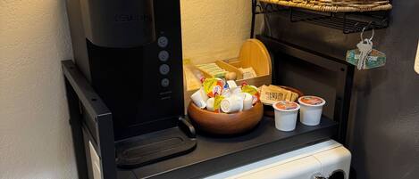 A kitchenette with a coffee maker, microwave, and a basket of bread.