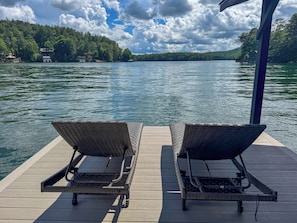 Deux fauteuils de jardin en osier, placés sur une jetée en bois, offrent une vue sur le lac.
