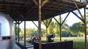 A covered outdoor area with a grill, picnic table, and seating area.