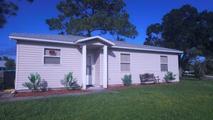 A single-story house with a front door, two windows, and a small porch area.