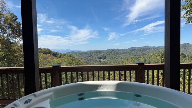 Ein Whirlpool auf einer Holzterrasse mit herrlicher Aussicht auf Berge und Bäume.