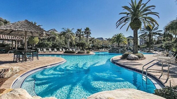 A swimming pool with lounge chairs and palm trees. - Designer 5BR • Sleeps 14 • Dog OK + Pool-Hot Tub (Destin)
