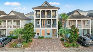 A two-story building with a central entrance, a covered porch, and a brick driveway. - Designer 5BR • Sleeps 14 • Dog OK + Pool-Hot Tub (Destin)