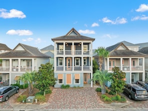 A two-story building with a central entrance, a covered porch, and a brick driveway. - Designer 5BR Destin • Sleeps 14 • Dog OK + Pool (Destin)