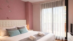 Ein Schlafzimmer mit Bett, Fernseher, einem Fenster mit Vorhängen und einer Wand mit Schmetterlingsstickern.