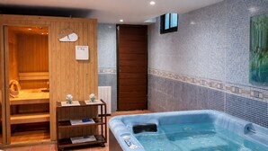 Ein Wellnessraum mit Whirlpool, Holzbastu und gefliesten Wänden.