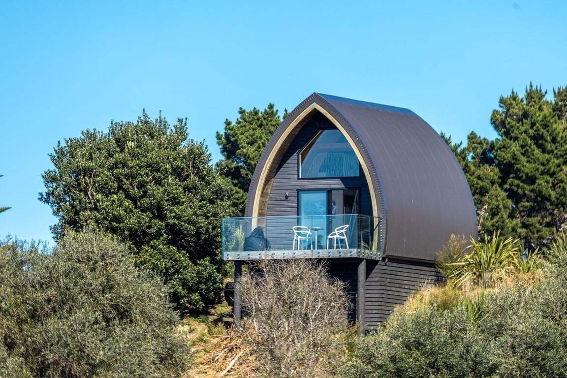 Een modern, koepelvormig gebouw met een balkon en buitenmeubilair.