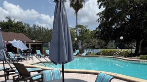 A poolside area with lounge chairs, a table, and umbrellas. - LUXE LOFT NAPLES (Naples)