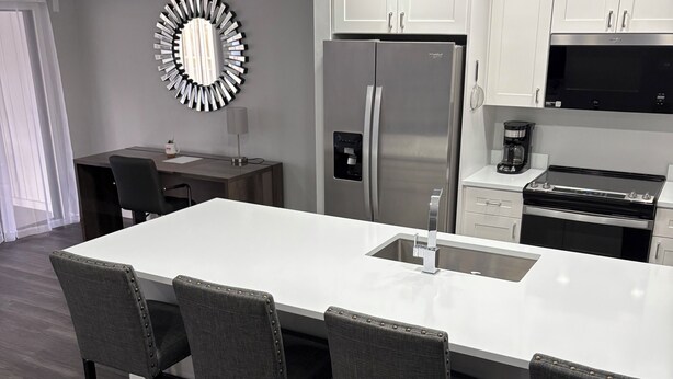 A modern kitchen with a large island, stainless steel appliances, and a unique wall mirror. - LUXE LOFT NAPLES (Naples)