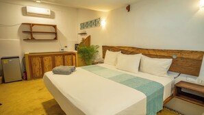 Una camera d'albergo con un letto grande, una testiera in legno, una piccola scrivania e un condizionatore d'aria a parete.