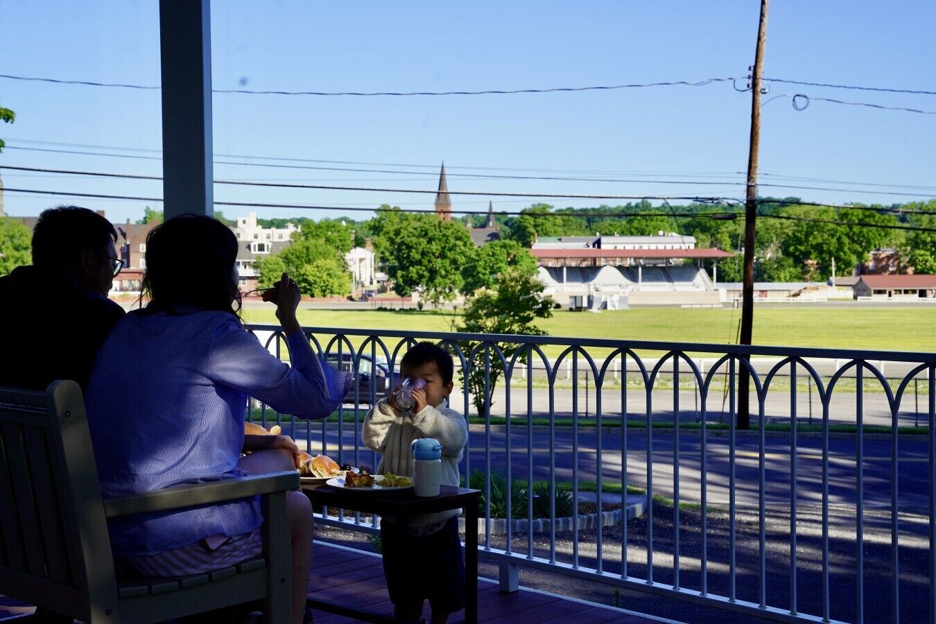 Varanda com vista para uma cidade, mesa com comida e uma criança bebendo.