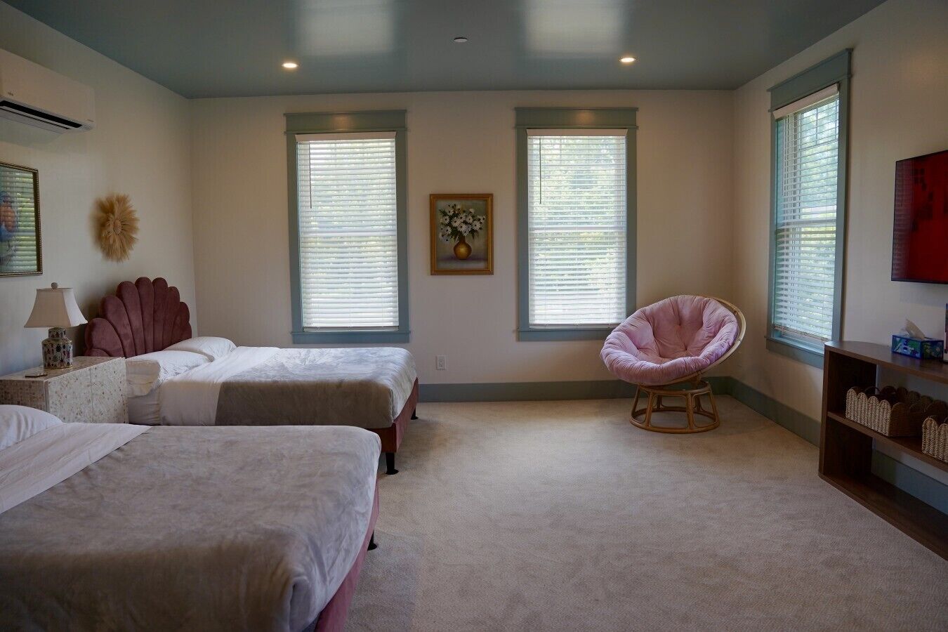 A bedroom with two beds, a chair, and a TV.