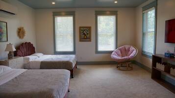 A bedroom with two beds, a chair, and a TV.