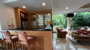 A modern kitchen with a central island, bar stools, and a dining area with a sofa and chairs. - No7 Double Suite, Rainbow Arokaya Welnes (Khlong Khuean)