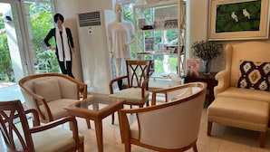 A room with wooden chairs, a glass-top table, a sofa, and a mannequin. - No7 Double Suite, Rainbow Arokaya Welnes (Khlong Khuean)