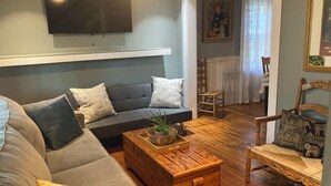 A living room with a grey sofa, wooden coffee table, and a TV mounted on the wall. - Soothing getaway farmhouse in Leeds near Hudson, Grace’s cafe, the creek, HITS. (Catskill)