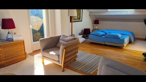 A modern bedroom with a sofa, a bed with blue bedding, a wooden floor, and a window with blinds. - BEACH FOREST CALM NATURE (Six-Fours-les-Plages)