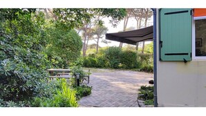 A garden pathway leading to a building with a green door and a window. - BEACH FOREST CALM NATURE (Six-Fours-les-Plages)
