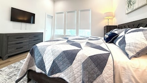A bedroom with a bed, a dresser, a TV, and a window with blinds. - The Pearl, 3 bedrooms townhouse, Medical Center (Houston)