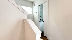 A modern staircase with white walls and wooden steps leading to a bathroom. - The Pearl, 3 bedrooms townhouse, Medical Center (Houston)