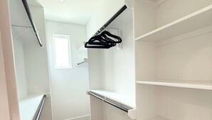 A narrow hallway with white walls, wooden flooring, and a black hanger rack on the right wall. - The Pearl, 3 bedrooms townhouse, Medical Center (Houston)