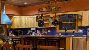 A kitchen with wooden cabinets, hanging pots, a stove, and a dishwasher. - Cozy up on Lake Osakis (Osakis)