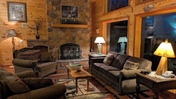 A cozy log cabin interior with a stone fireplace, wooden walls, and a large window. - Cozy up on Lake Osakis (Osakis)