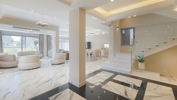 A spacious living area with a modern design, featuring a large seating area, a staircase, and a dining area. - 4-bedroom villa in palm hills compound with garden (Giza Governorate)