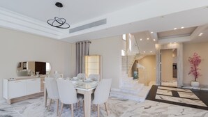A modern dining area with a marble floor, white furniture, and a staircase leading to another level. - 4-bedroom villa in palm hills compound with garden (Giza Governorate)
