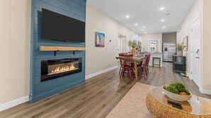 Una sala de estar moderna con chimenea, un comedor y una cocina al fondo.