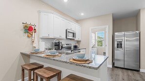 Una cocina con armarios blancos, un refrigerador de acero inoxidable y una encimera de granito.