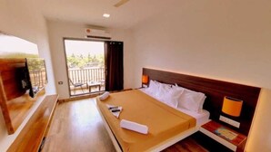 A hotel room with a bed, a TV, a balcony, and a window. - Hotel Samudra City (Alibag)