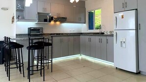 A modern kitchen with grey cabinets, a built-in microwave, a refrigerator, and a ceiling fan. - Vacation, Apartment at the Beach Club Casa Blanca, Same, Ecuador (Same)