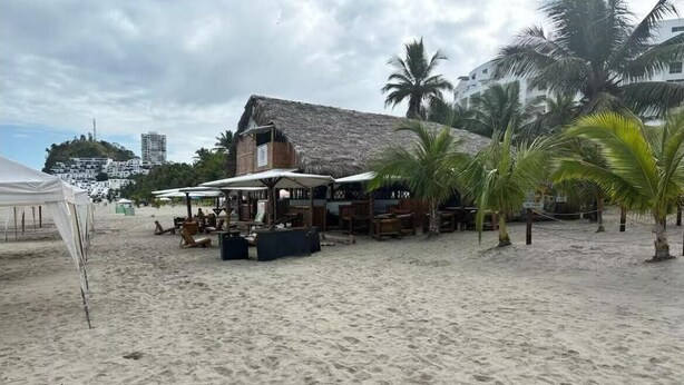 A beachside bar with outdoor seating, palm trees, and a thatched-roof building. - Vacation, Apartment at the Beach Club Casa Blanca, Same, Ecuador (Same)