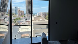 A modern living room with a large sliding glass door leading to a balcony, offering a city view. - Cozy 2-bedroom apartment in amazing Mazatlán with AC (Mazatlán)