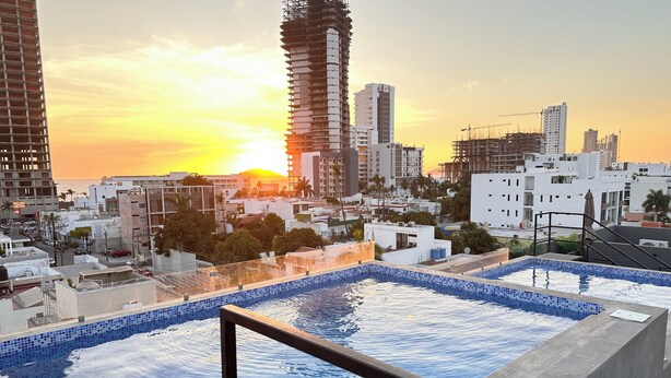 A rooftop pool with a cityscape view at sunset. - Cozy 2-bedroom apartment in amazing Mazatlán with AC (Mazatlán)