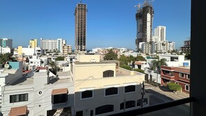 A cityscape with two high-rise buildings under construction, surrounded by various other buildings and a clear blue sky. - Cozy 2-bedroom apartment in amazing Mazatlán with AC (Mazatlán)