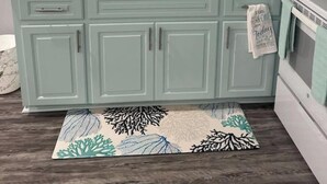 A kitchen with teal cabinets, a double sink, a stove, and a patterned rug. - BB On The Bayou  (Gautier)