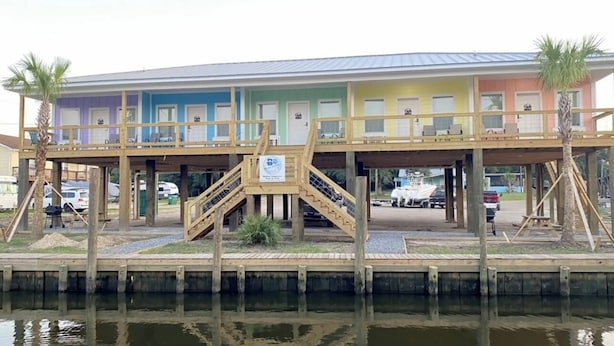 A multi-story building with a wooden deck and stairs leading to the upper floors. - BB On The Bayou  (Gautier)