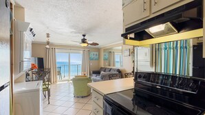 Cocina compacta con estufa, refrigerador y comedor con vista al océano.