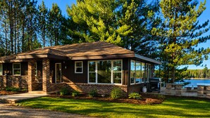 A two-story house with a brick exterior, large windows, and a deck area.