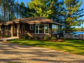A two-story house with a brick exterior, large windows, and a deck area.