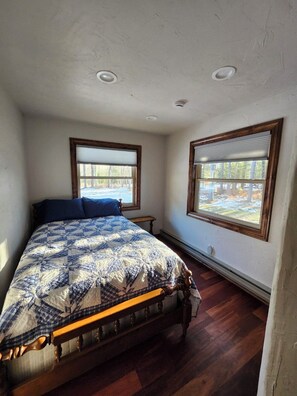 A bedroom with a large bed, two windows, and a ceiling light fixture. - Lily Bay Lodge (Mercer)