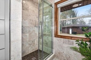 A glass-enclosed shower with a view of the outdoors. - Lily Bay Lodge (Mercer)