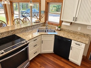 A kitchen with granite countertops, white cabinetry, a built-in dishwasher, and a stove.