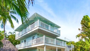Une maison à deux étages avec une piscine, entourée d’une végétation tropicale.