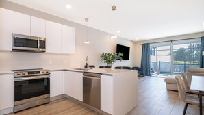 A modern kitchen with a built-in oven, microwave, and dishwasher, a dining area with a table and chairs, and a large window offering a view.