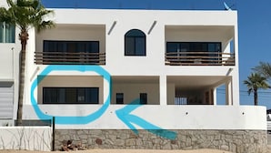 Un edificio moderno a due piani con balconi, una base in pietra e un cielo azzurro intenso.